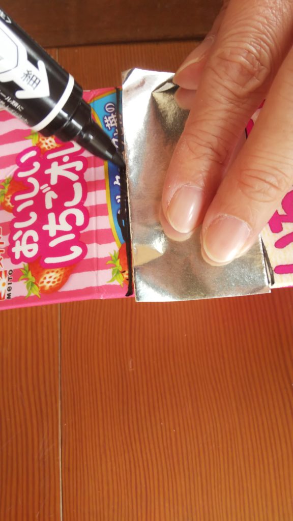 切った折り紙の1枚の幅に牛乳パックに印をつけて切る